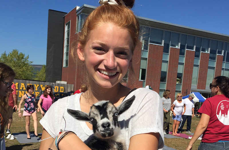 A young woman holding a baby goat.